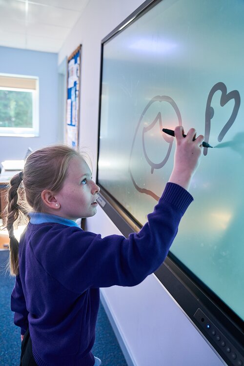 child writing on a large touch screen