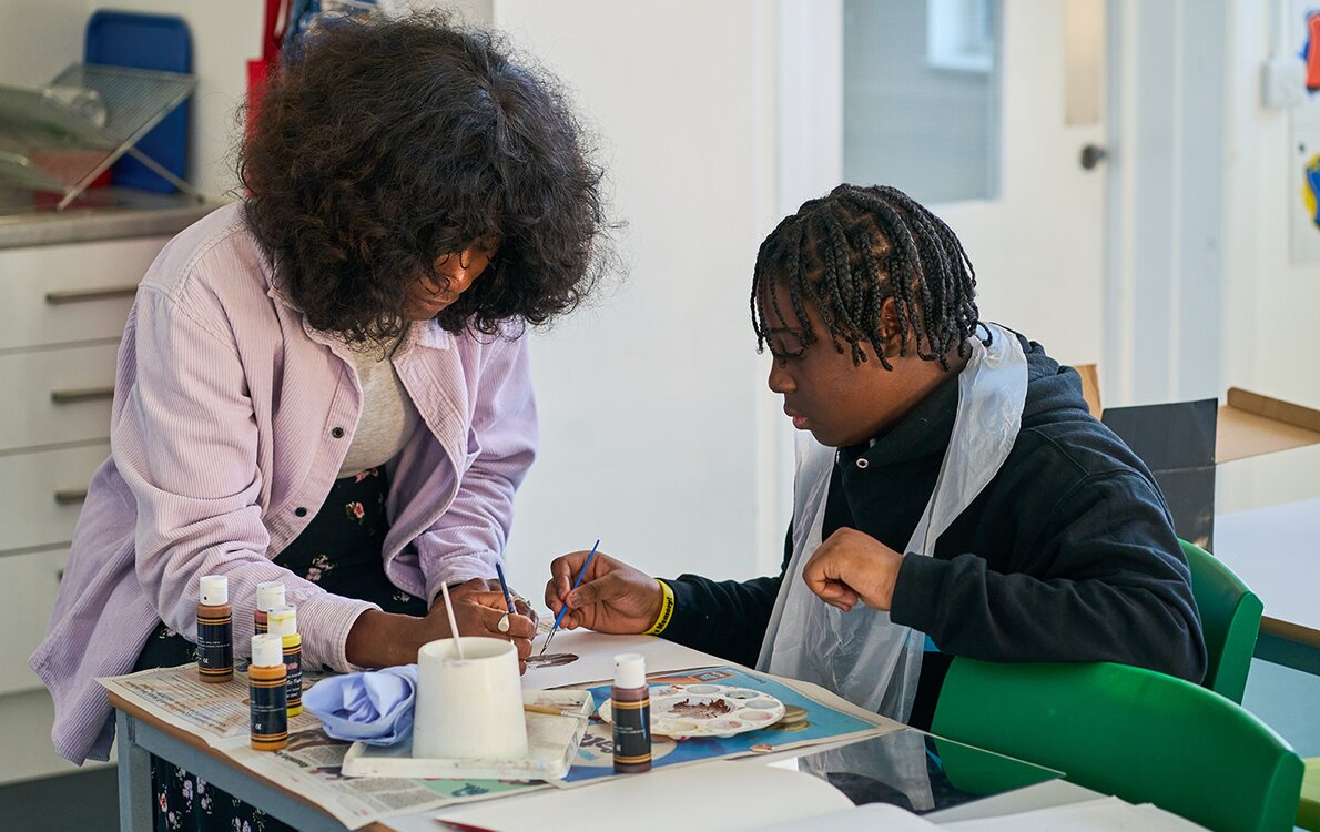 pupil working with art teacher in art room