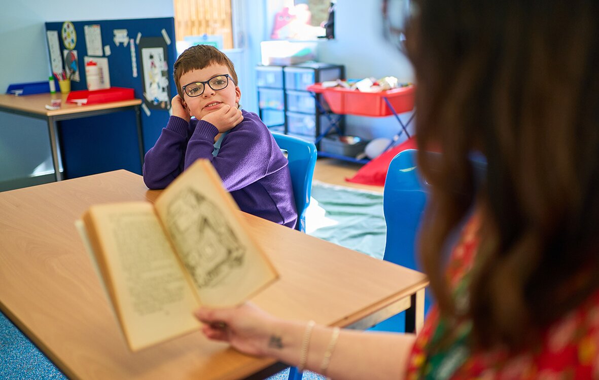 adult reads to a child in school uniform