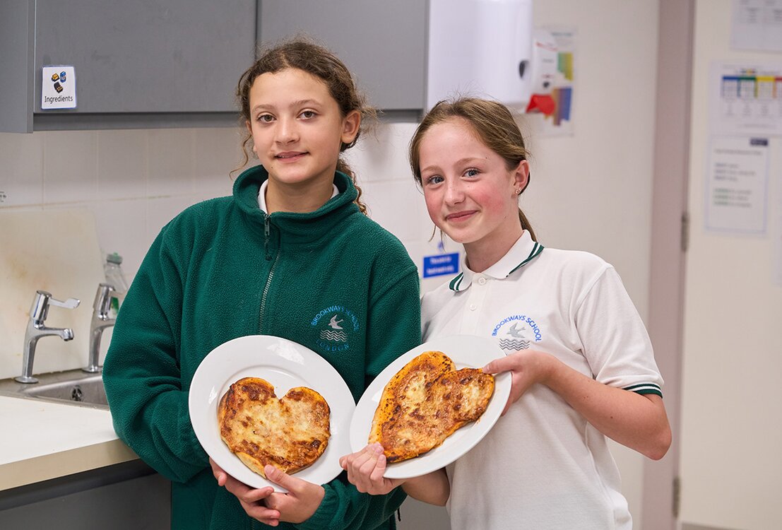 two children holding love heart shaped pizzas up