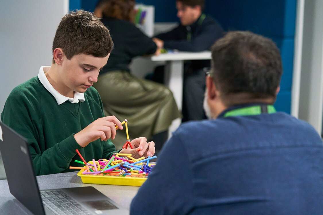 child plays with magnetic toy watched by member of staff