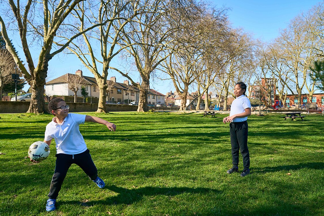 twp children playing with a ball in a grassy park