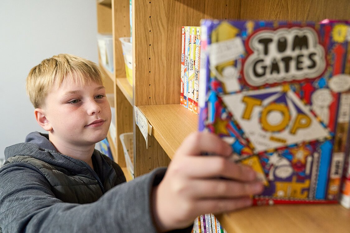 child picking book off of shelf