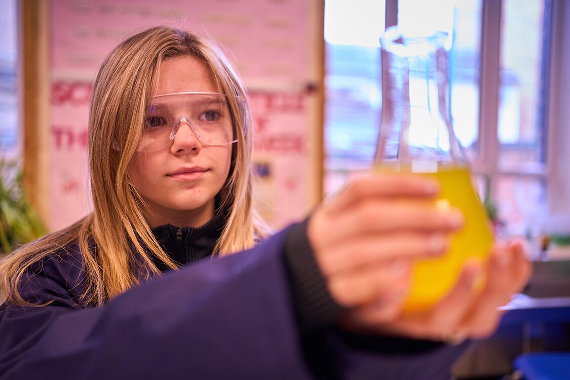 girl holding conical flask of yellow liquid