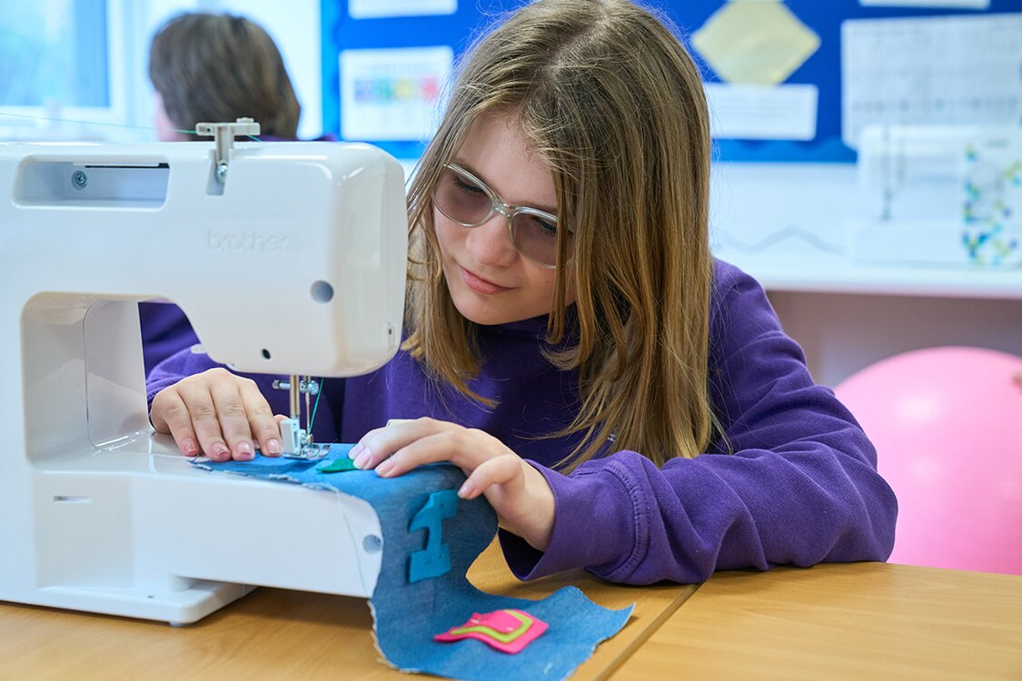 school child using a sewing machine 