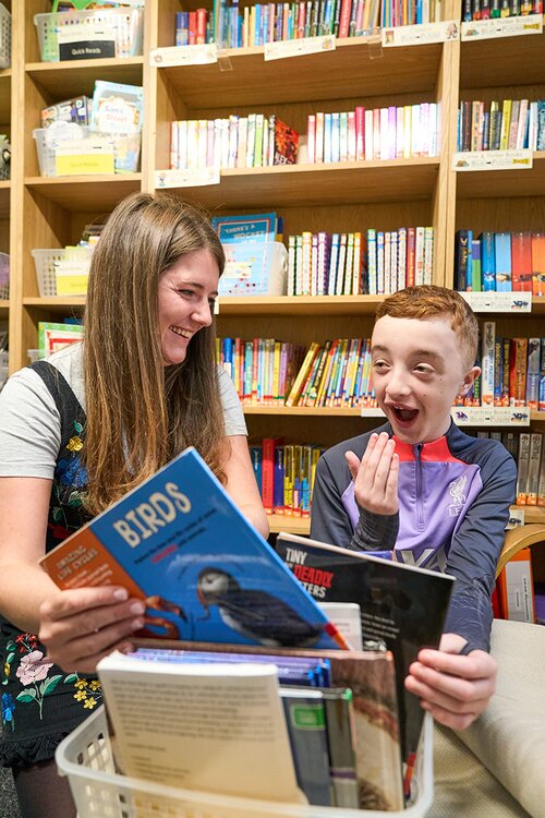 child reading in library with adult