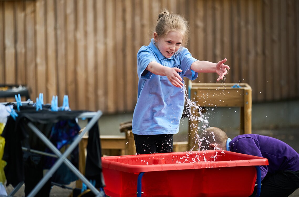 girl in school uniform playing with water trough