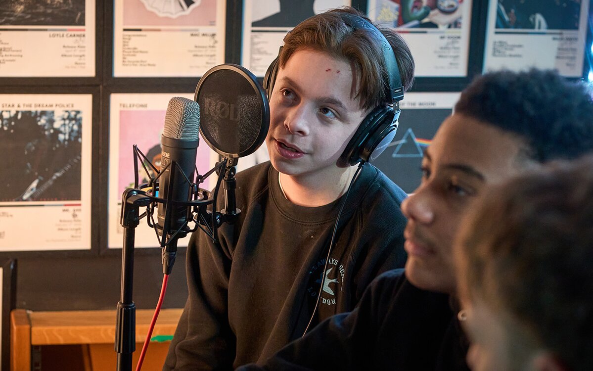 pupil sits at a microphone in a recording studio