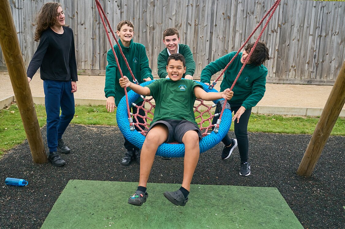 children push a child on a basket swing