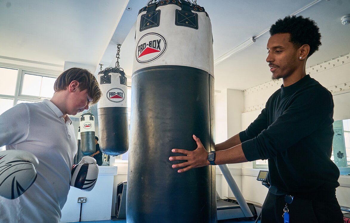 pupil working out with a punch bag held by an adult