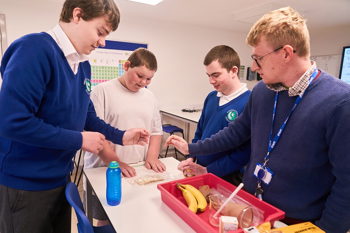 pupils talk with teacher around a table during a science lesson