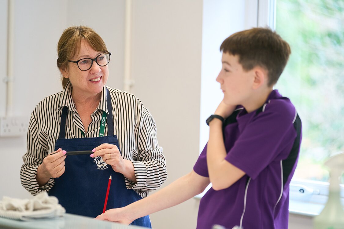 adult talking to pupil in school uniform
