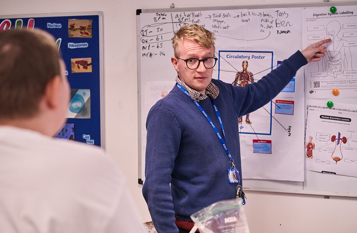 teacher points to a diagram on wall