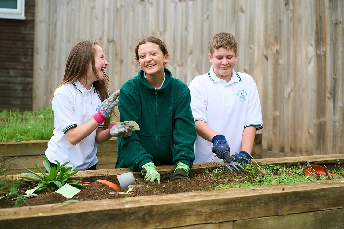 three children gardening with trowls