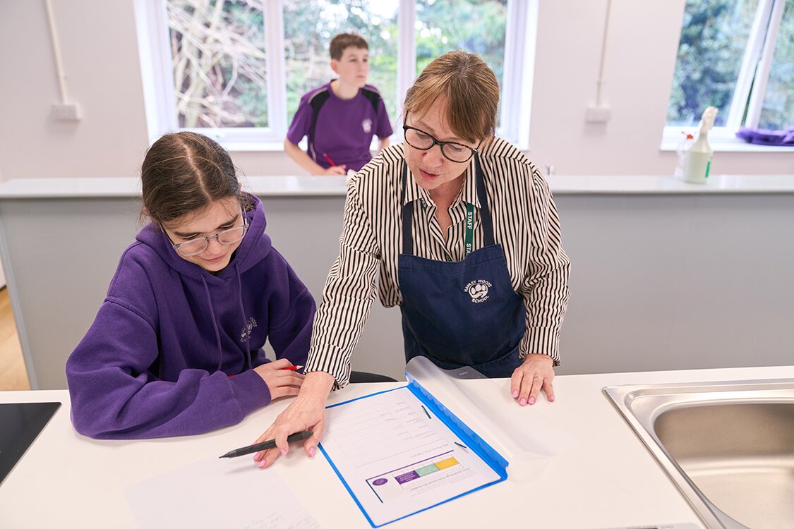 child in school uniform talks with adult looking at a folder