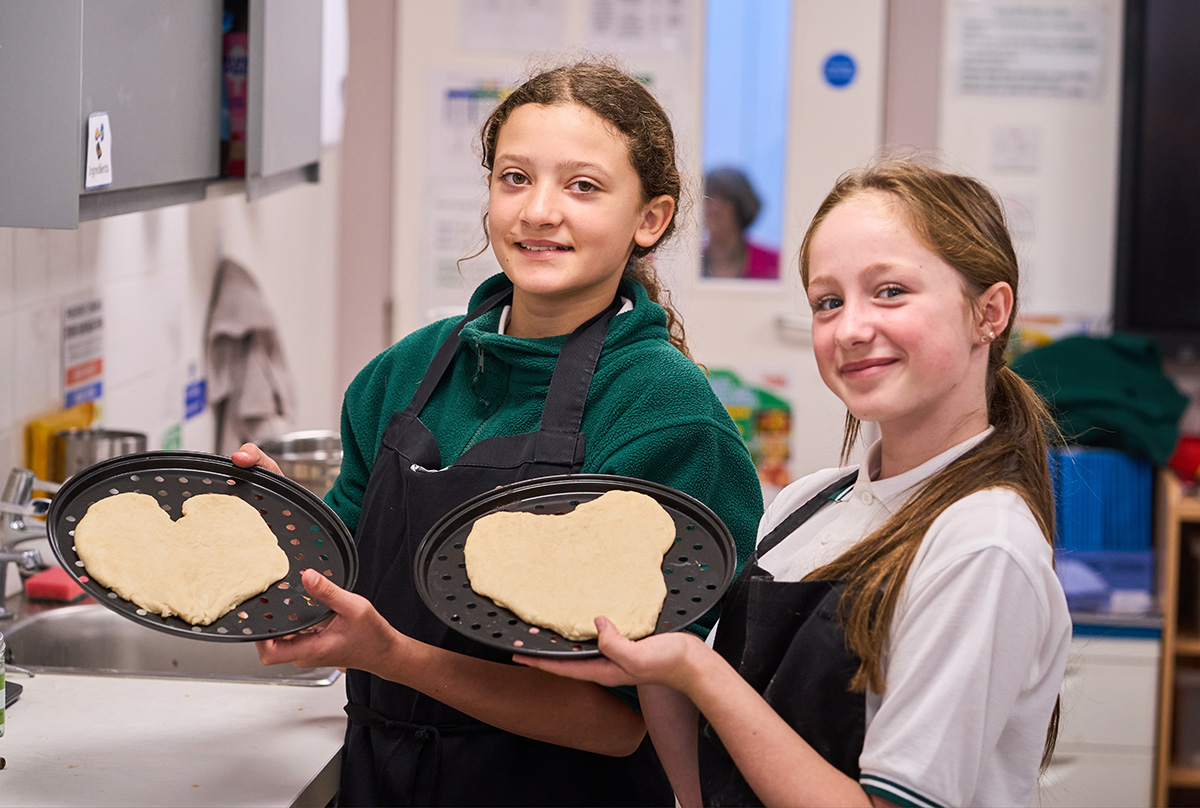 two children holding up love heart pizza bases