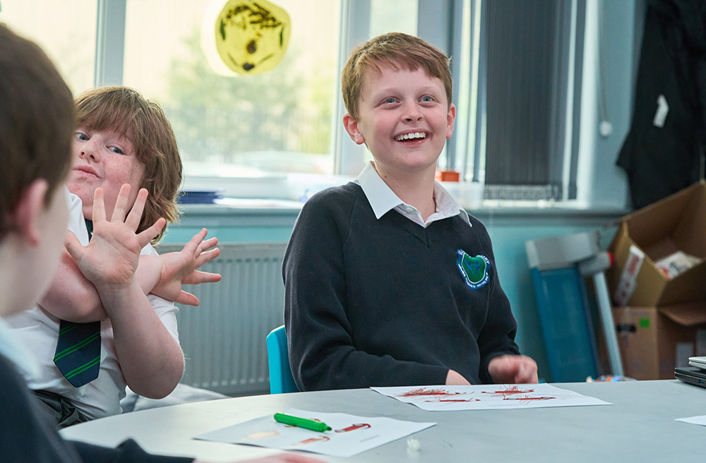 Pupils sit around a table one is smiling at the camera