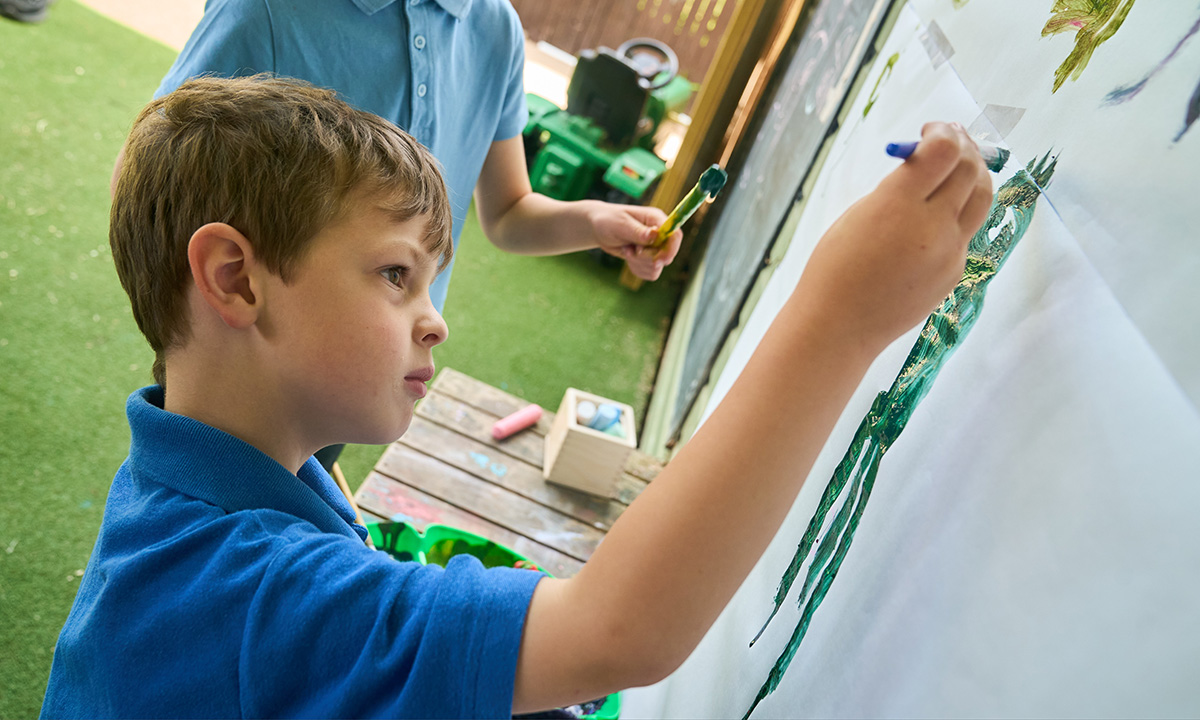 child painting on paper on a wall