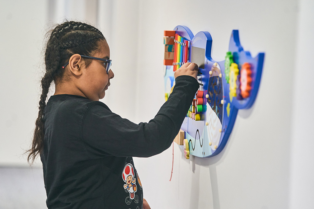 pupil plays with sensory toy on wall
