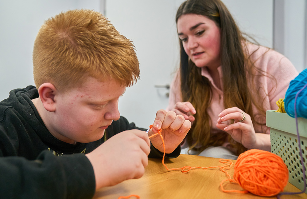 pupil crocheting with adult watching