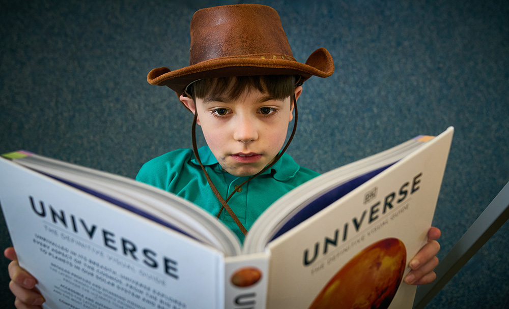 pupil wearing a cowboy hat reading a book